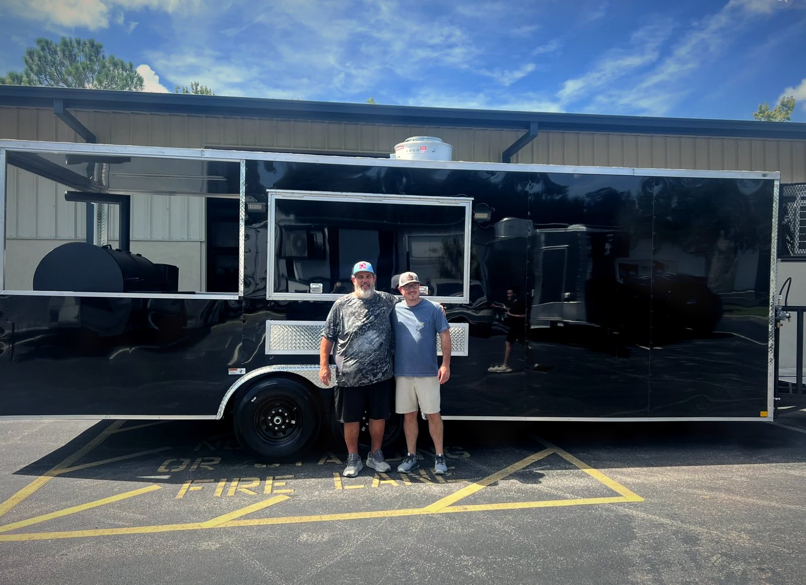 Bo and Nick standing in front of their brand-new black food truck the day they picked it up